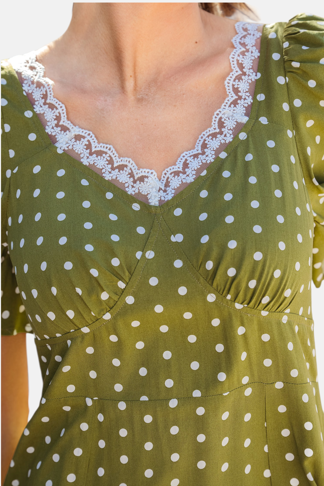 Olive polka dot midi dress close up detail showing white lace trimmed V-neckline and flutter sleeve