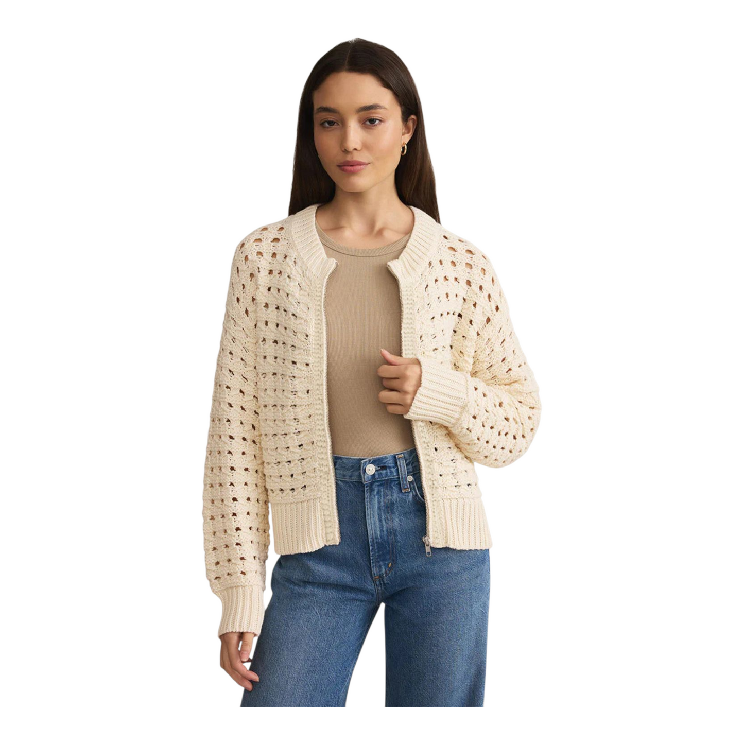 Woman wearing a beige open-knit cardigan over a beige top and blue jeans on a white background