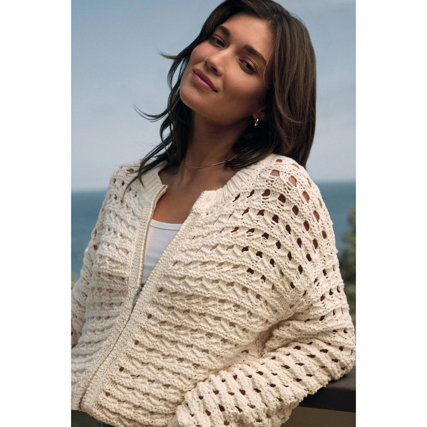 Woman wearing a beige knitted cardigan by the sea