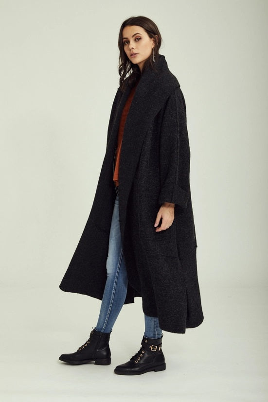 Woman wearing a long black coat on a white background