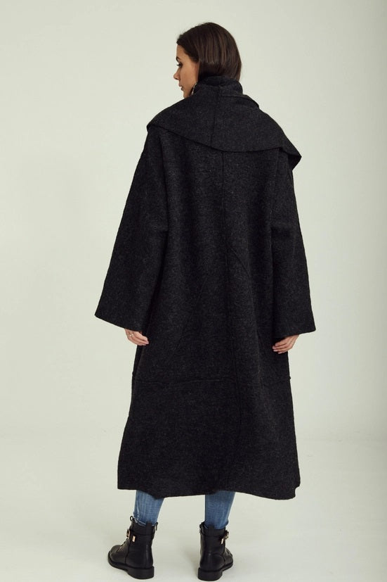 Person wearing a long black coat on a white background