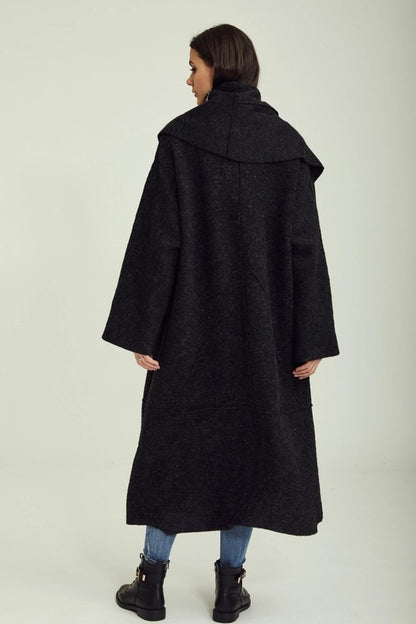 Person wearing a long black coat on a white background