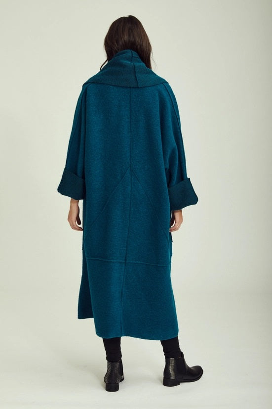 Person wearing a teal coat on a plain background