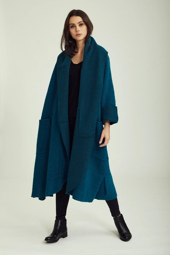 Woman wearing a teal coat on a white background