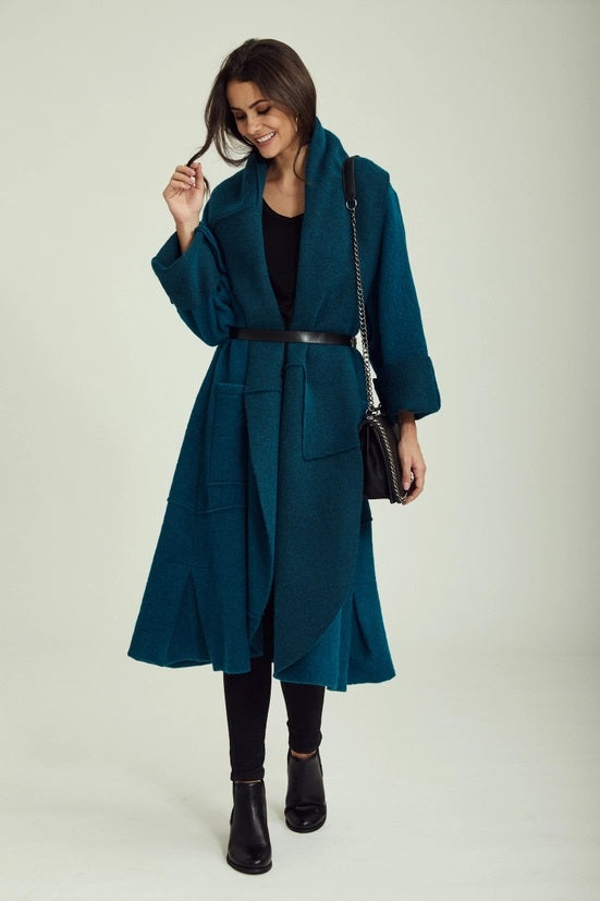 Woman wearing a teal coat with a white background