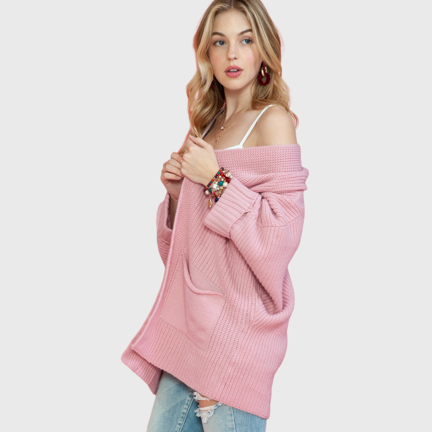 A side-angle view of the pink knit cardigan showcasing the deep knitted patch pockets and the voluminous, slouchy sleeve silhouette.