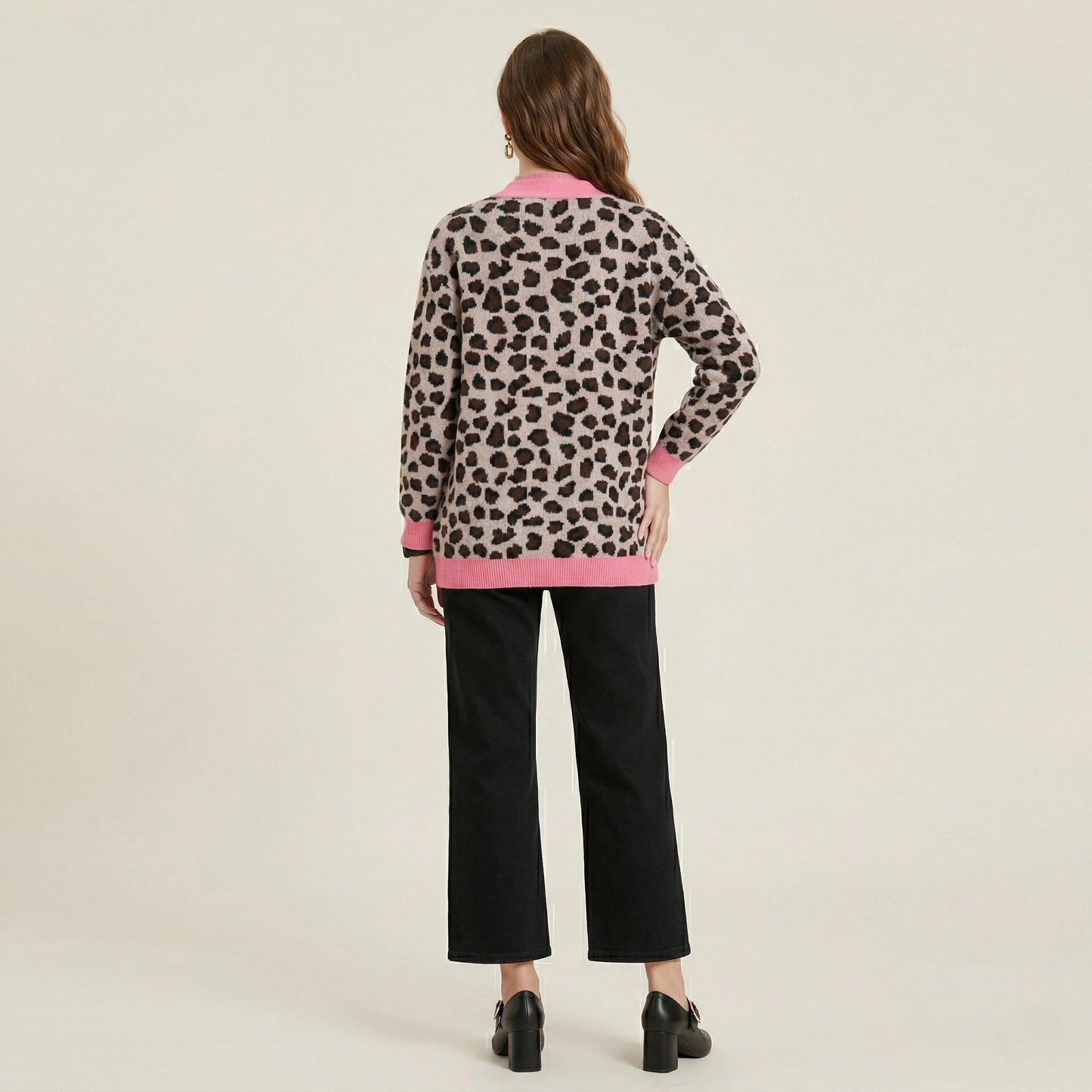 Back view of a model wearing a longline leopard print cardigan with pink trim, styled with black wide-leg trousers.