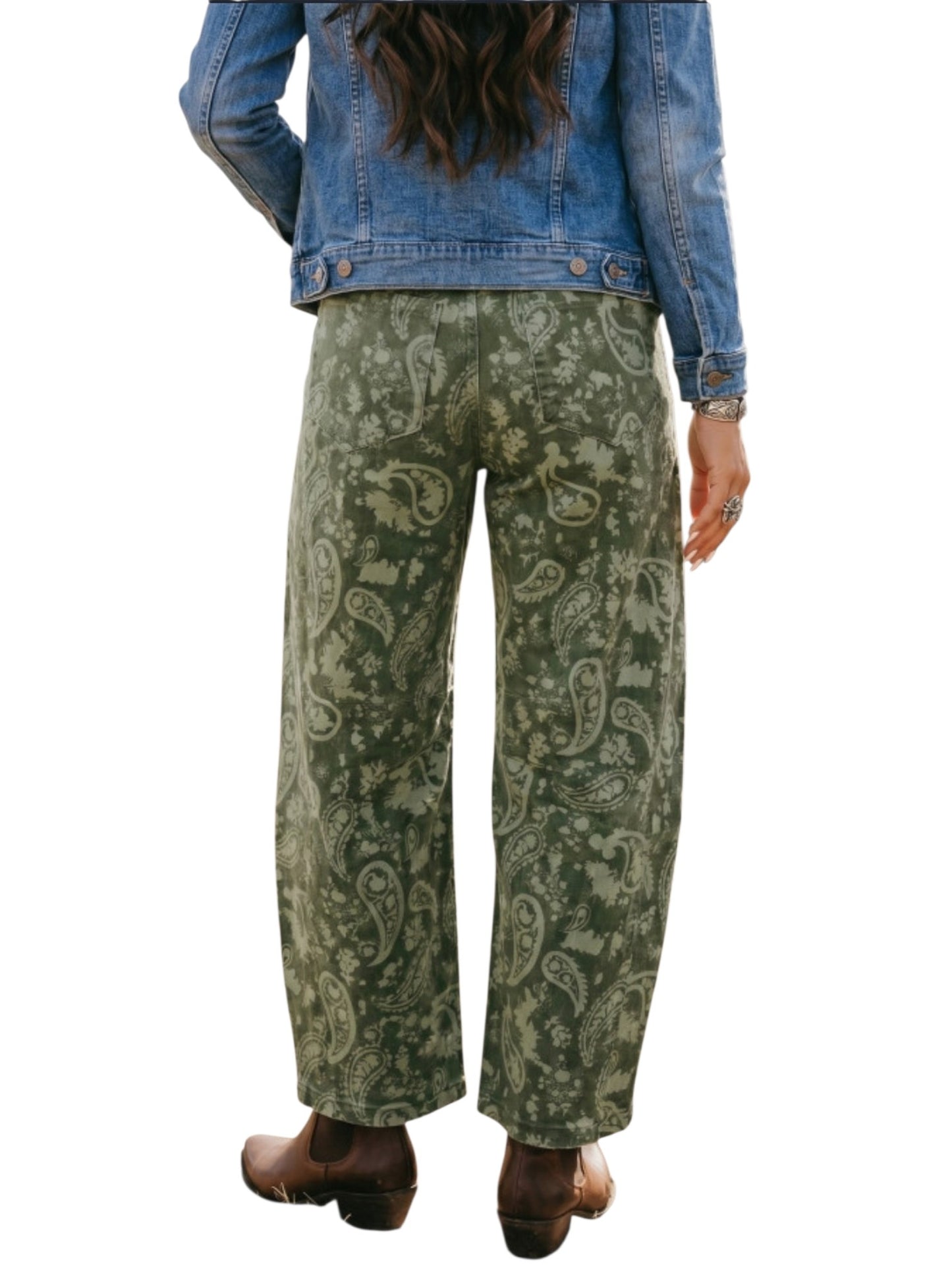 A person shown from the back wearing wide-leg green paisley pants, a blue denim jacket, and brown boots against a plain white background.