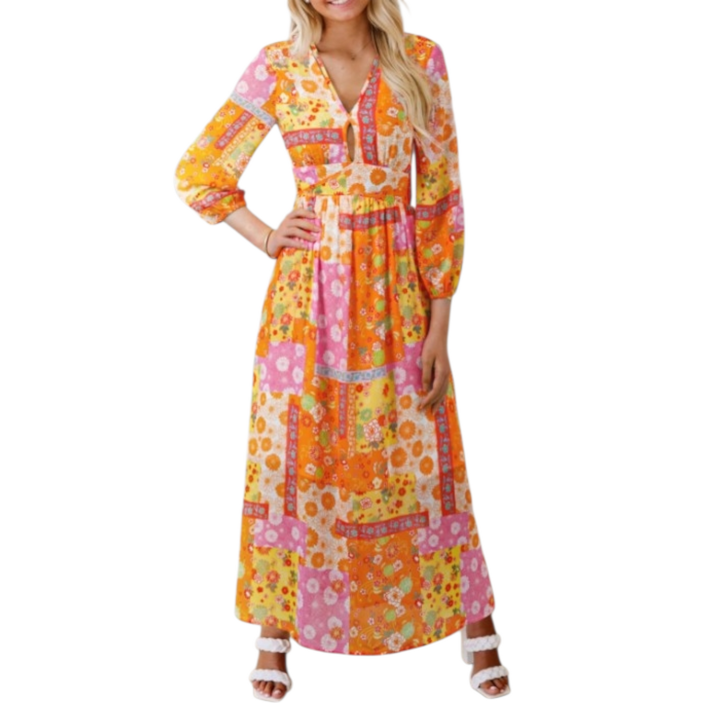Smiling woman wearing a full-length, long-sleeved maxi dress with a colorful orange, pink, and yellow floral patchwork print and a V-neckline.