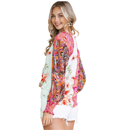 Back view of a woman wearing a multi-coloured patchwork floral viscose blouse with a V-neckline and button-down front.