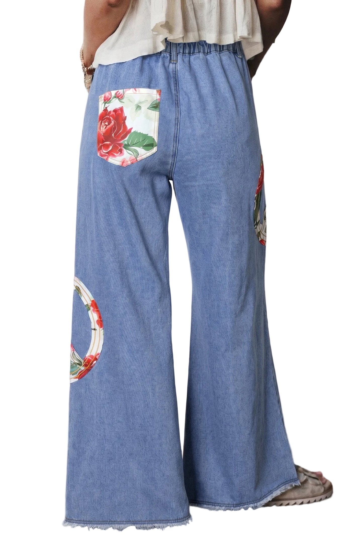 Blue denim pants with floral and circular designs on a plain background