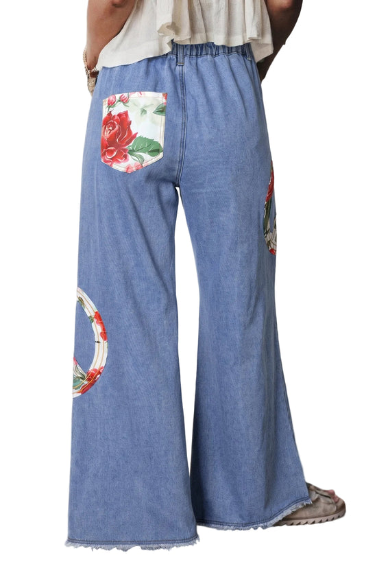 Blue denim pants with floral and circular designs on a plain background