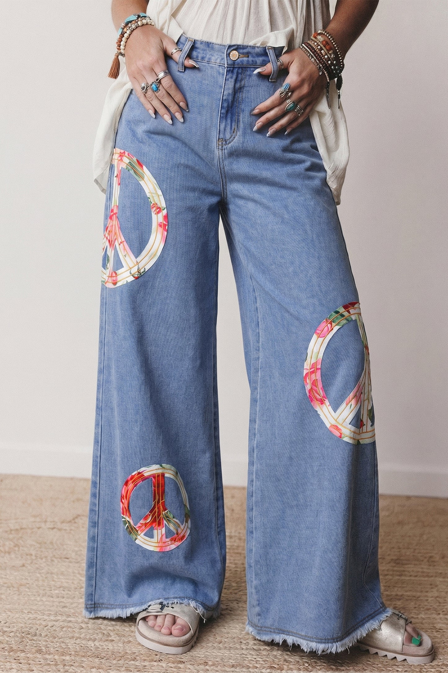 Wide-leg jeans with peace symbol patches worn by a person.