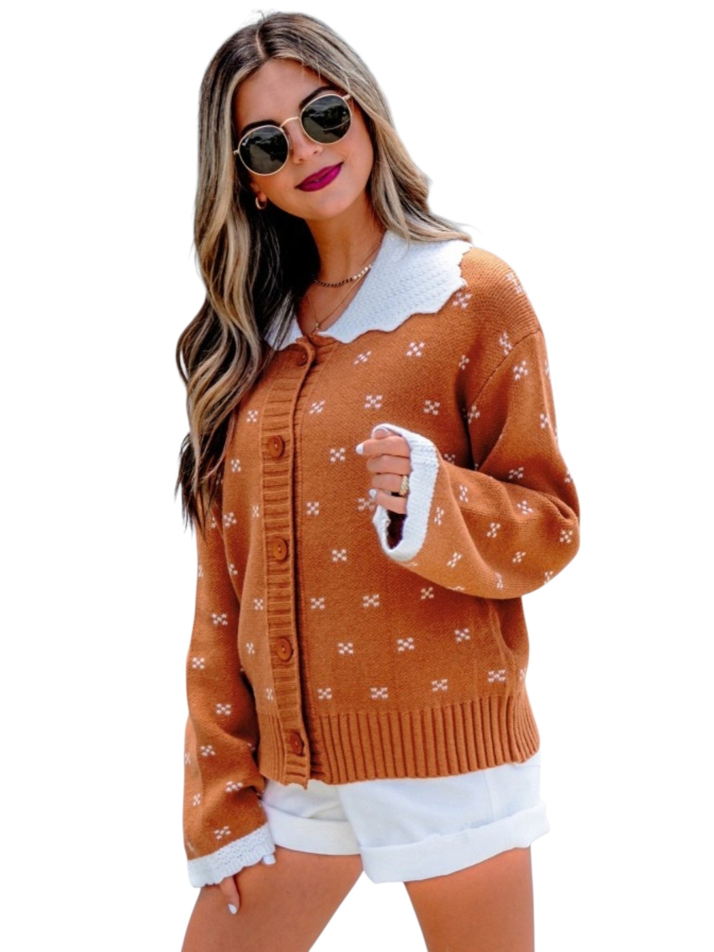A woman modeling a rust-orange knit cardigan with a white scalloped collar and white trim, paired with white shorts against a plain white background.