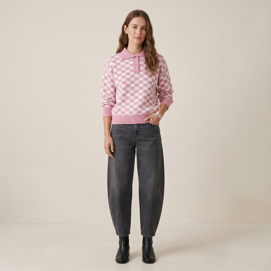 Women wearing pink checkerboard polo knit jumper with grey barrel leg jeans and black ankle boots full length view