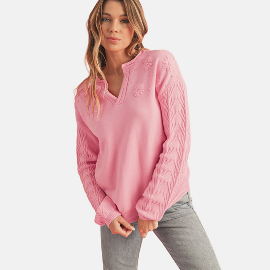 Pink floral embroidery cable sleeve knit sweater front view showing tonal daisy embroidery and notched V-neckline detail