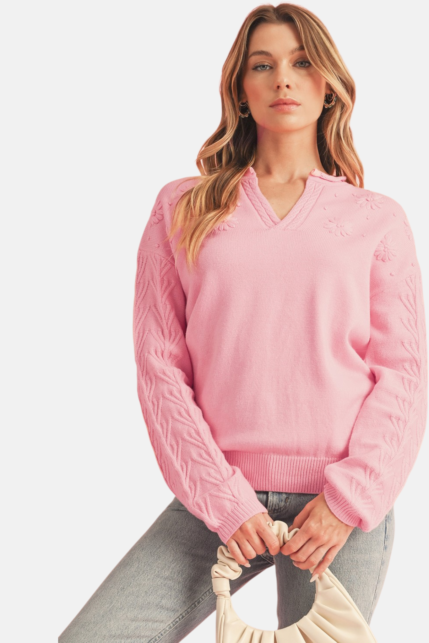 Pink floral embroidery cable sleeve knit sweater styled with grey jeans and cream ruched handbag front view