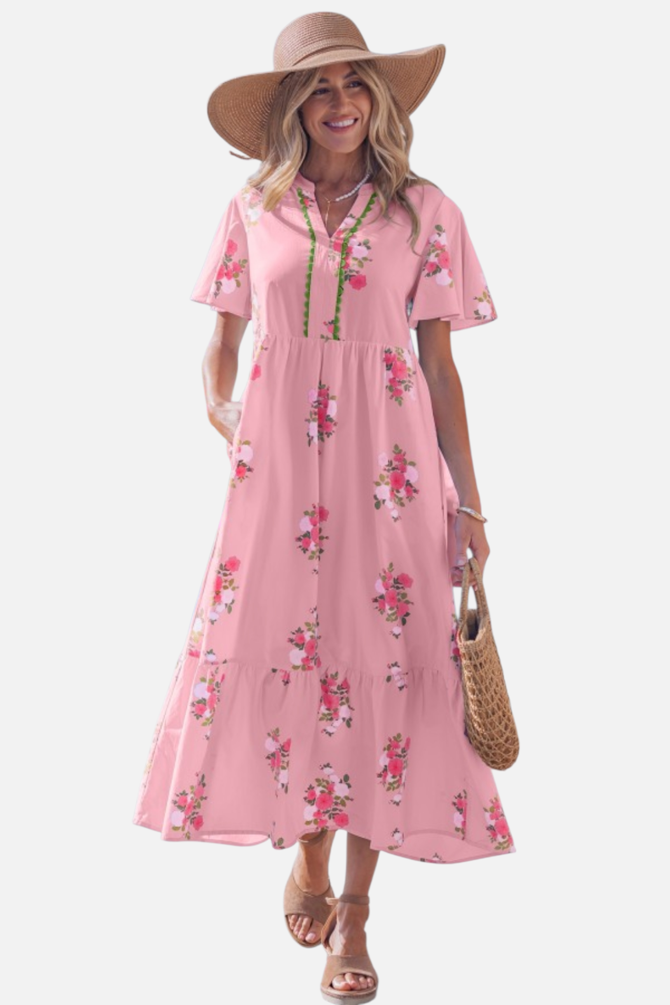 A woman wearing a light pink floral maxi dress with pink rose patterns, featuring flutter short sleeves and a notched neckline.