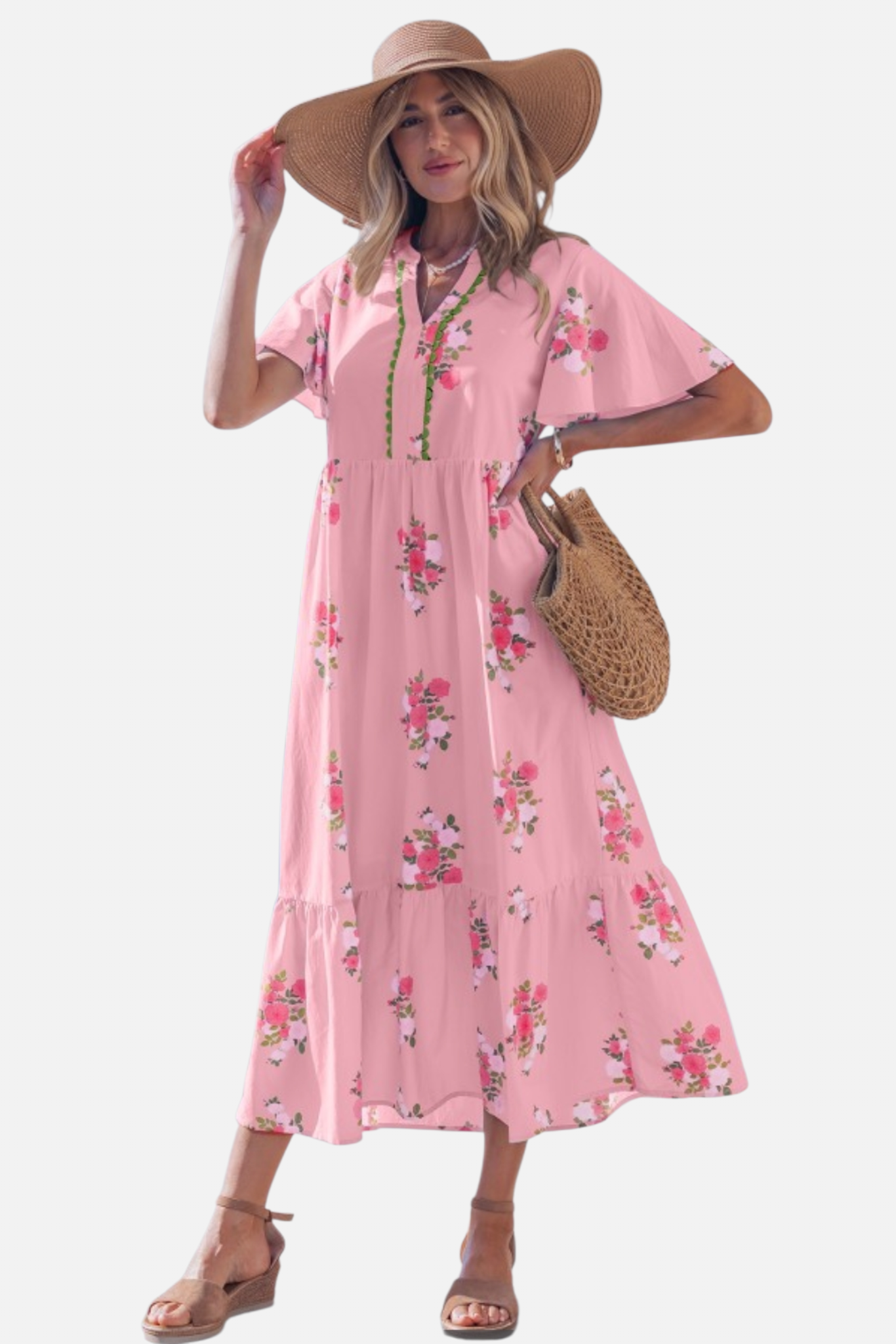 Woman wearing a pink floral dress with a straw hat and bag on a white background