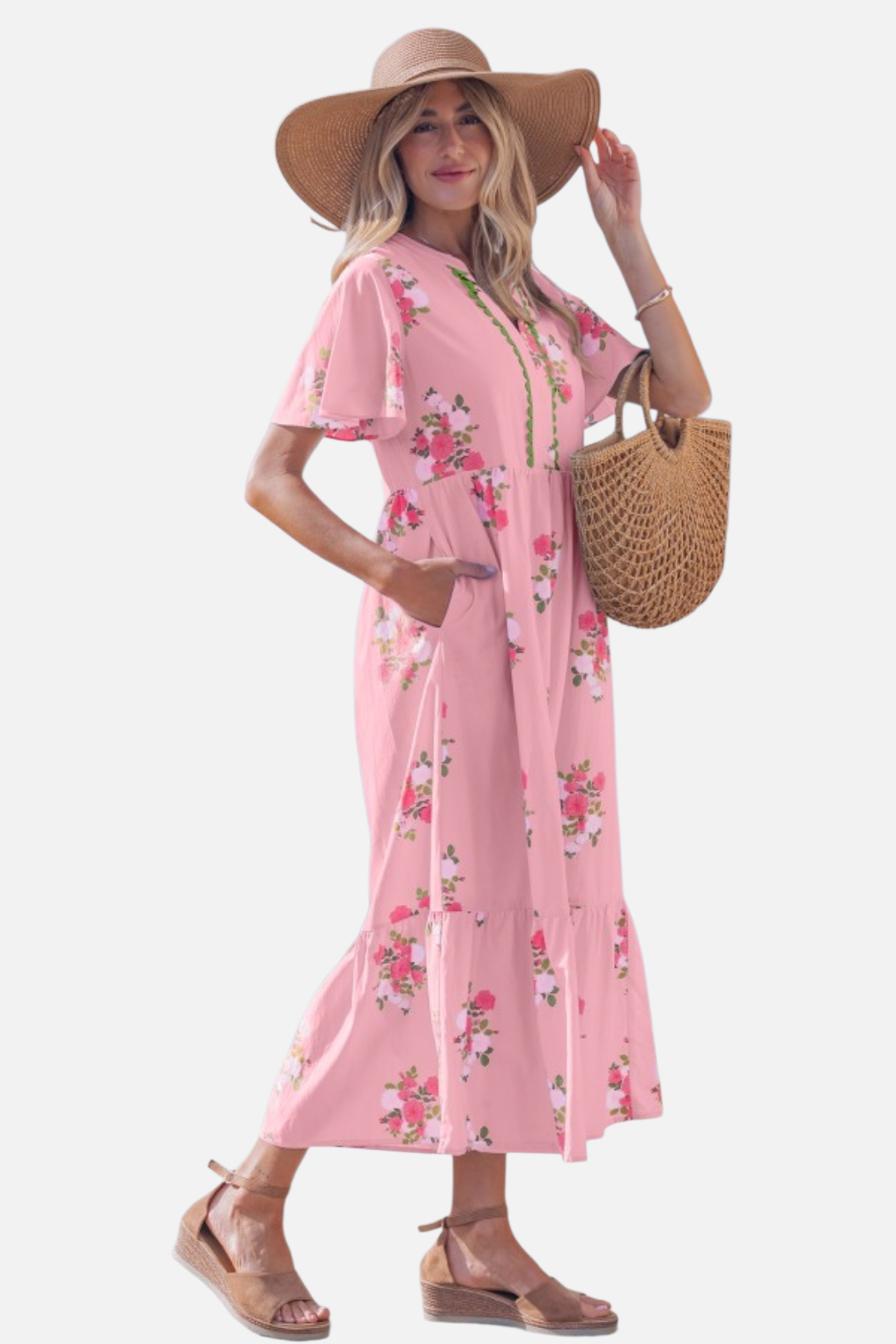 Side view of a  woman wearing a light pink floral maxi dress with pink rose patterns, featuring flutter short sleeves, side pockets and a notched neckline.