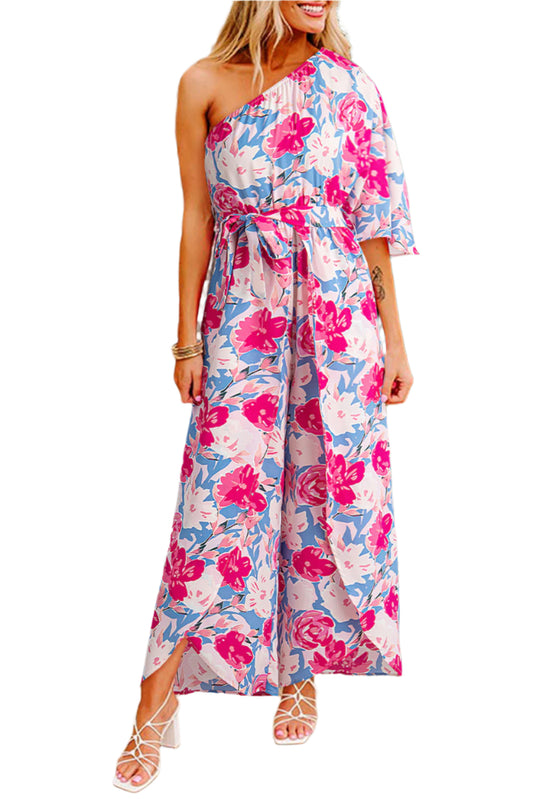 Model wearing a pink floral jumpsuit with a removable belt and wide leg hem, styled with sandals.