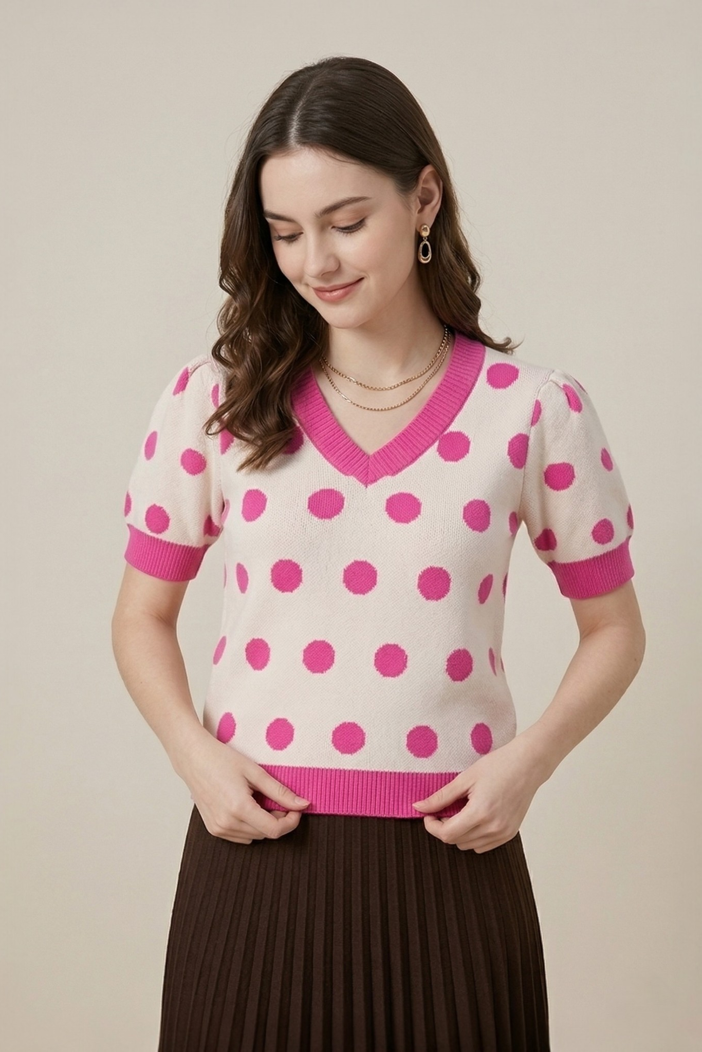 Close-up of a model in a pink polka dot V-neck knit top, highlighting the soft knit texture and puffed shoulder detail.