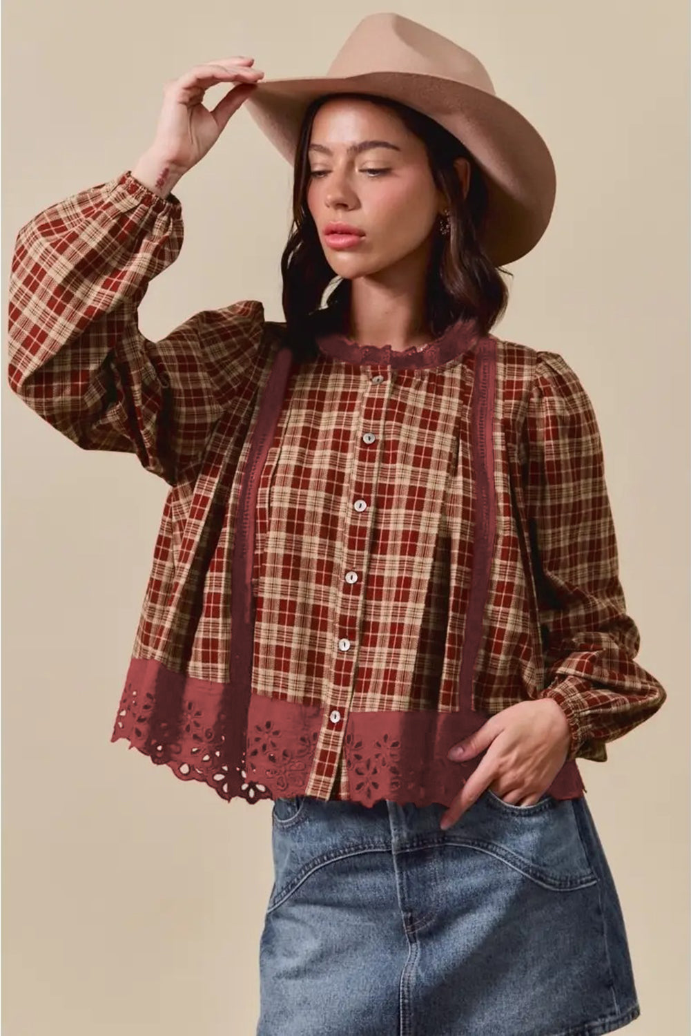 Woman wearing a plaid shirt, denim skirt, and beige hat against a beige background