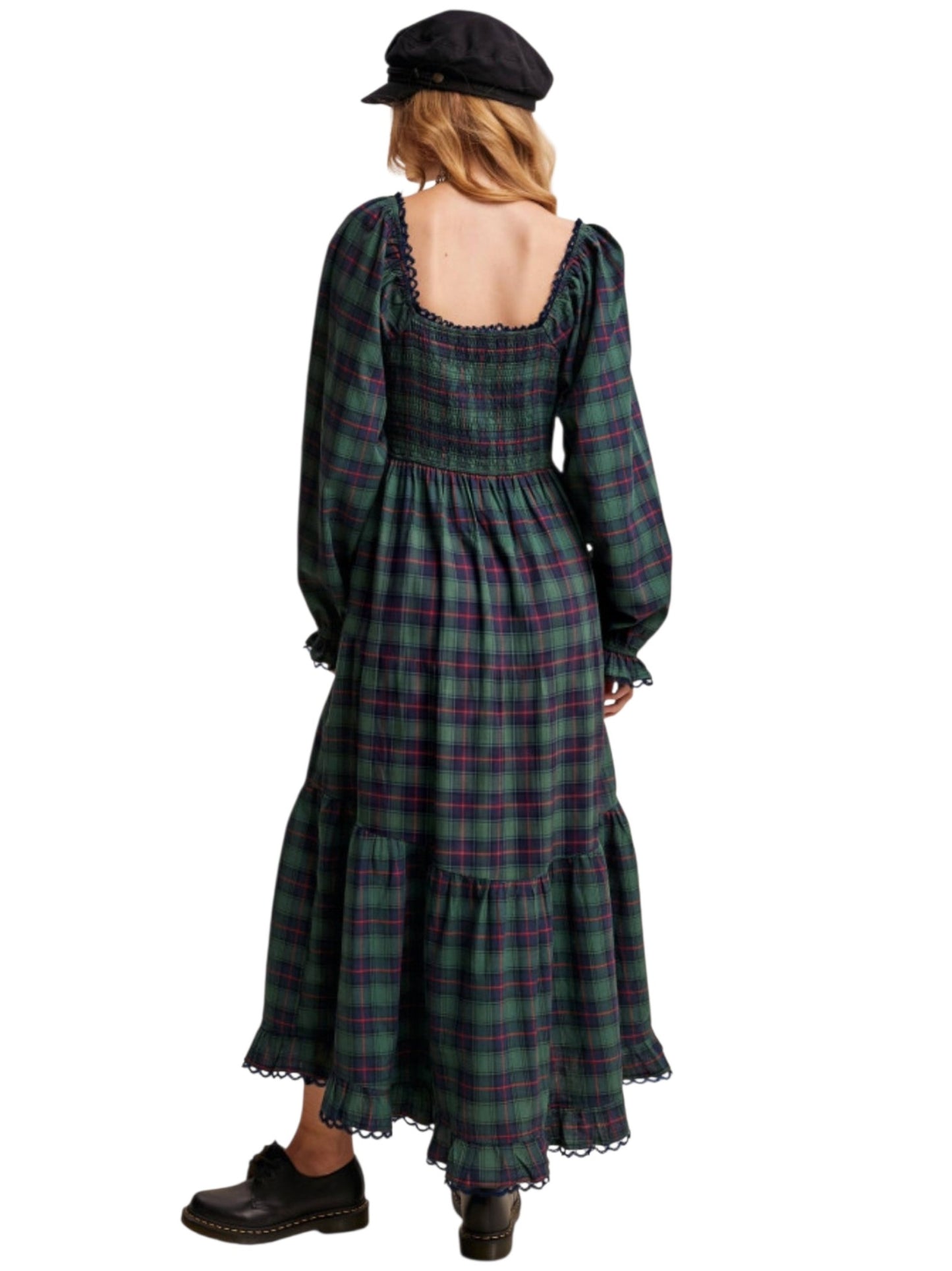 A woman shown from the back wearing a long-sleeved dark green plaid midi dress with a smocked bodice, ruffled trim, and a black beret, set against a plain white background.