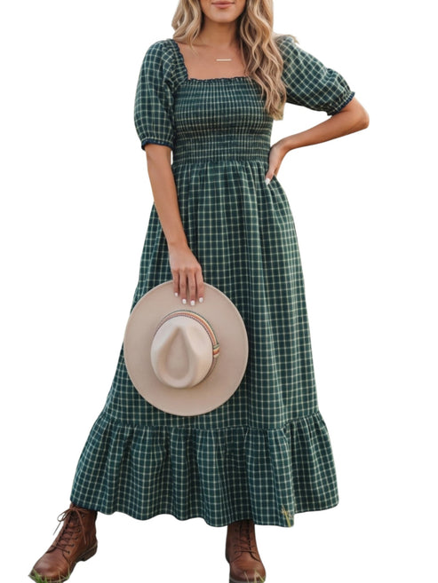 Woman wearing a green plaid dress holding a beige hat on a white background