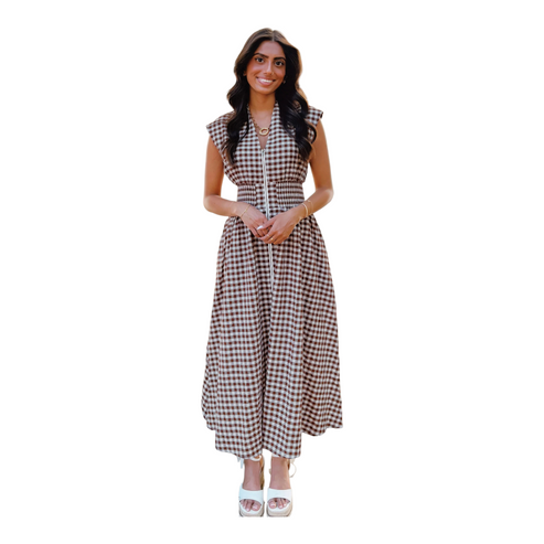 A woman wearing a sleeveless chocolate brown and white gingham maxi dress with a full-length front zipper and a wide smocked waistband.