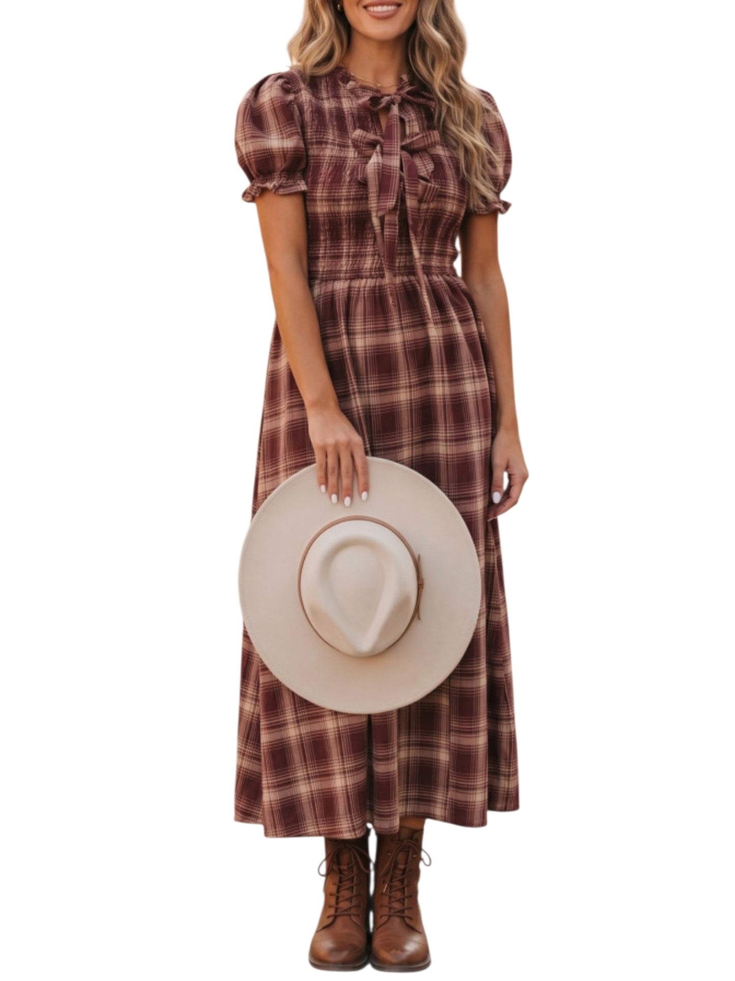 A woman wearing a brown and burgundy plaid midi dress with puff sleeves and a bow at the collar, holding a beige wide-brim hat. She is wearing brown lace-up boots against a plain white background.