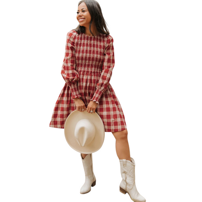 Woman wearing a red plaid dress with white boots and a beige hat on a white background