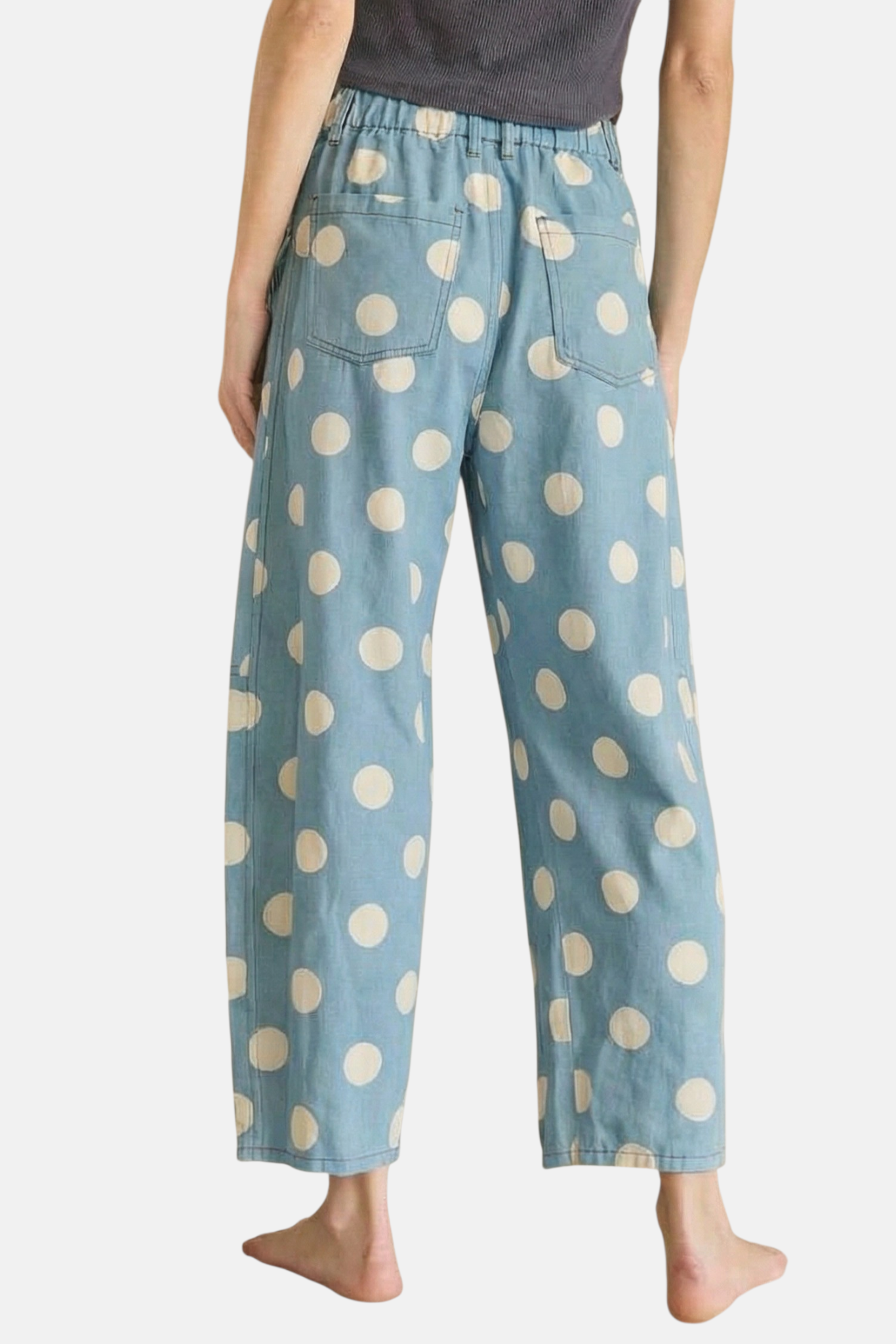 Rear view of sky blue wide-leg jeans with a cream polka dot print and functional back patch pockets.