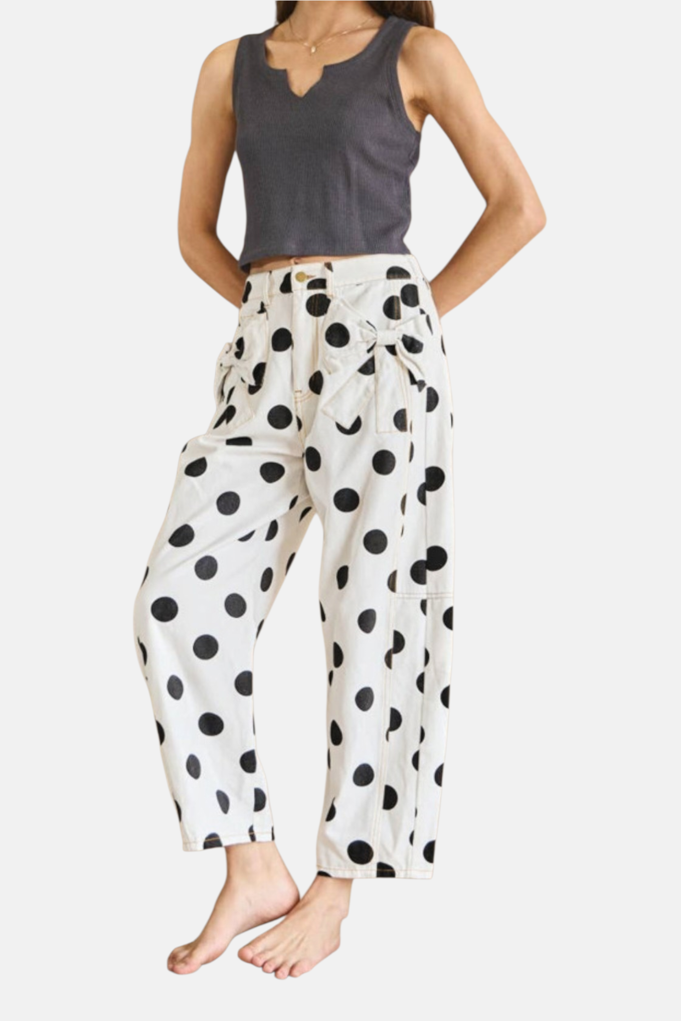Full-length shot of a model wearing white and black polka dot jeans showcasing the relaxed, cropped silhouette.