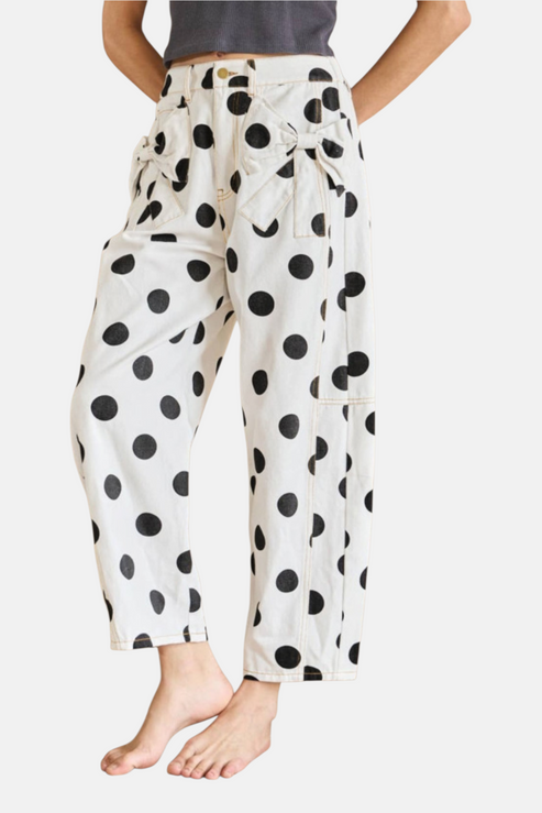 Front lifestyle view of the white polka dot wide-leg jeans featuring a structured waist and feminine bow accents.
