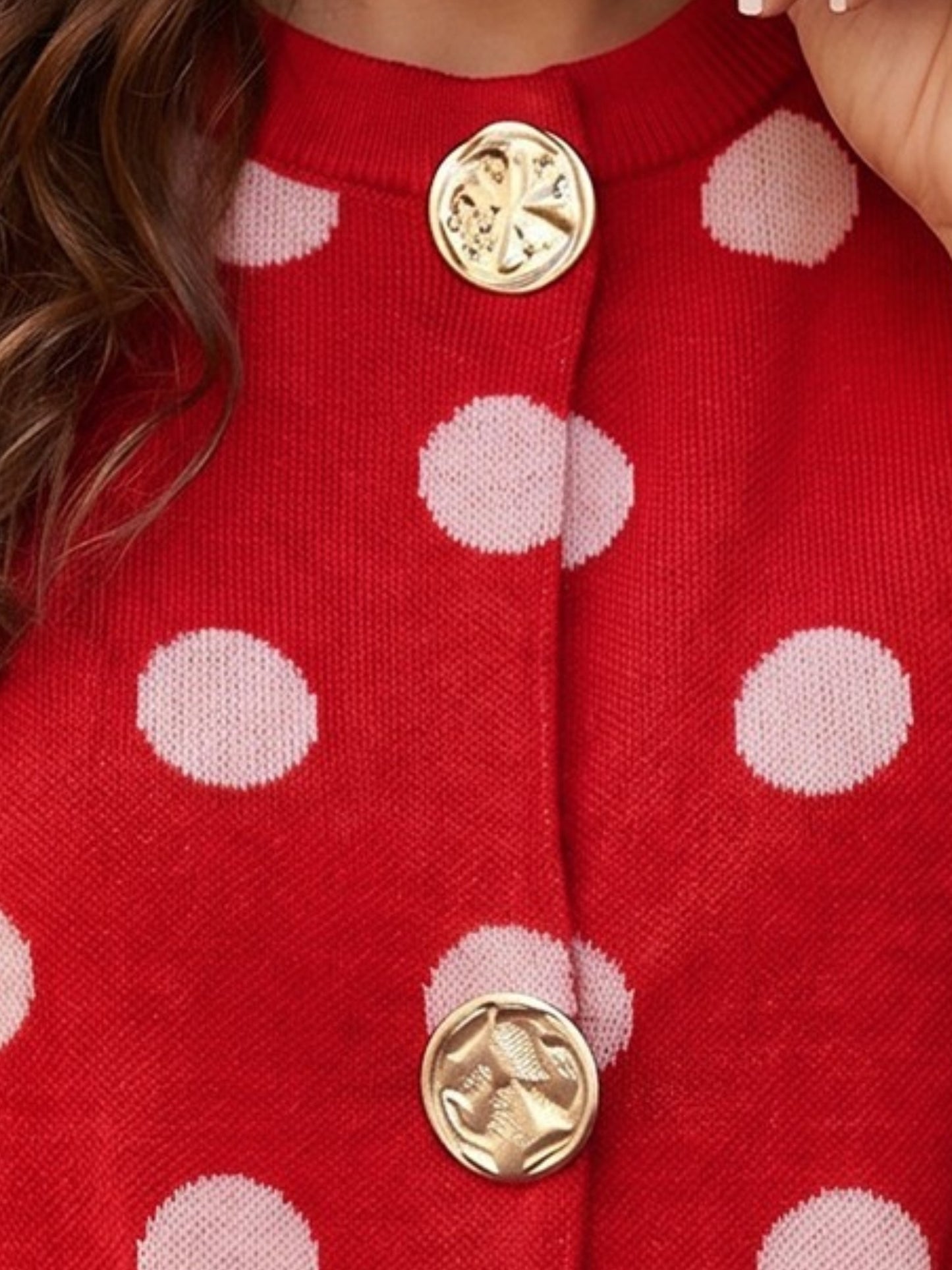 Closed up view of a polka dot button knit top with gold buttons 