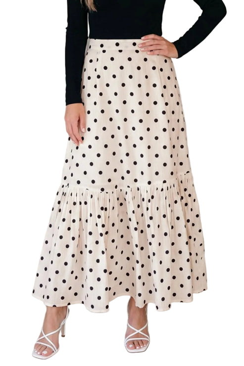 Woman wearing a polka dot skirt with a plain background