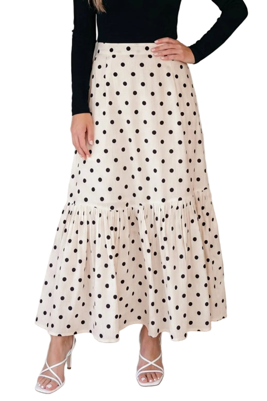 Woman wearing a polka dot skirt with a plain background