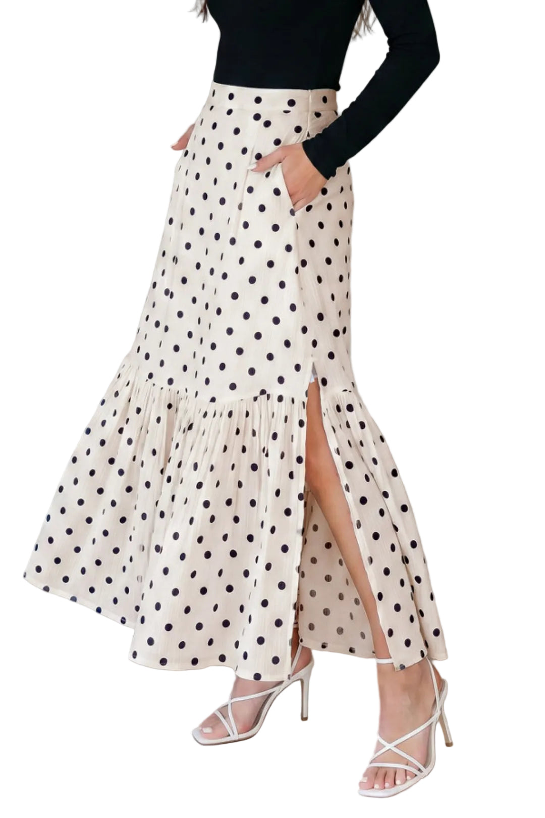 Woman wearing a polka dot skirt with a high slit on a plain background