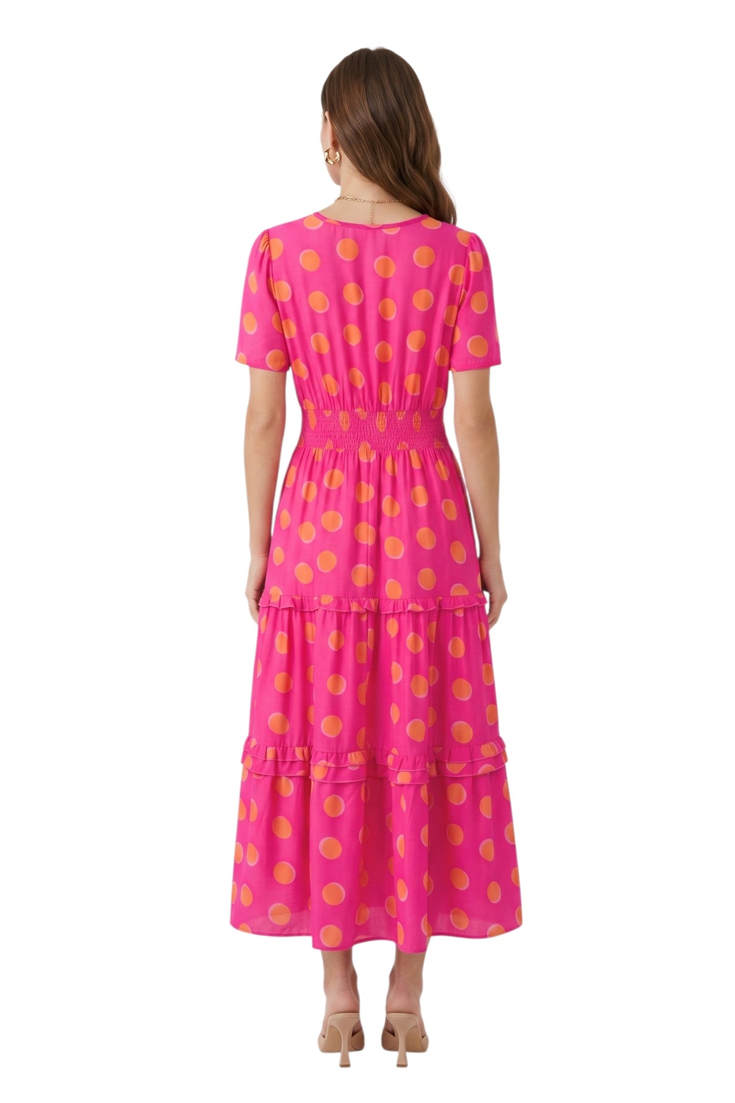 Woman wearing a pink dress with yellow polka dots on a white background