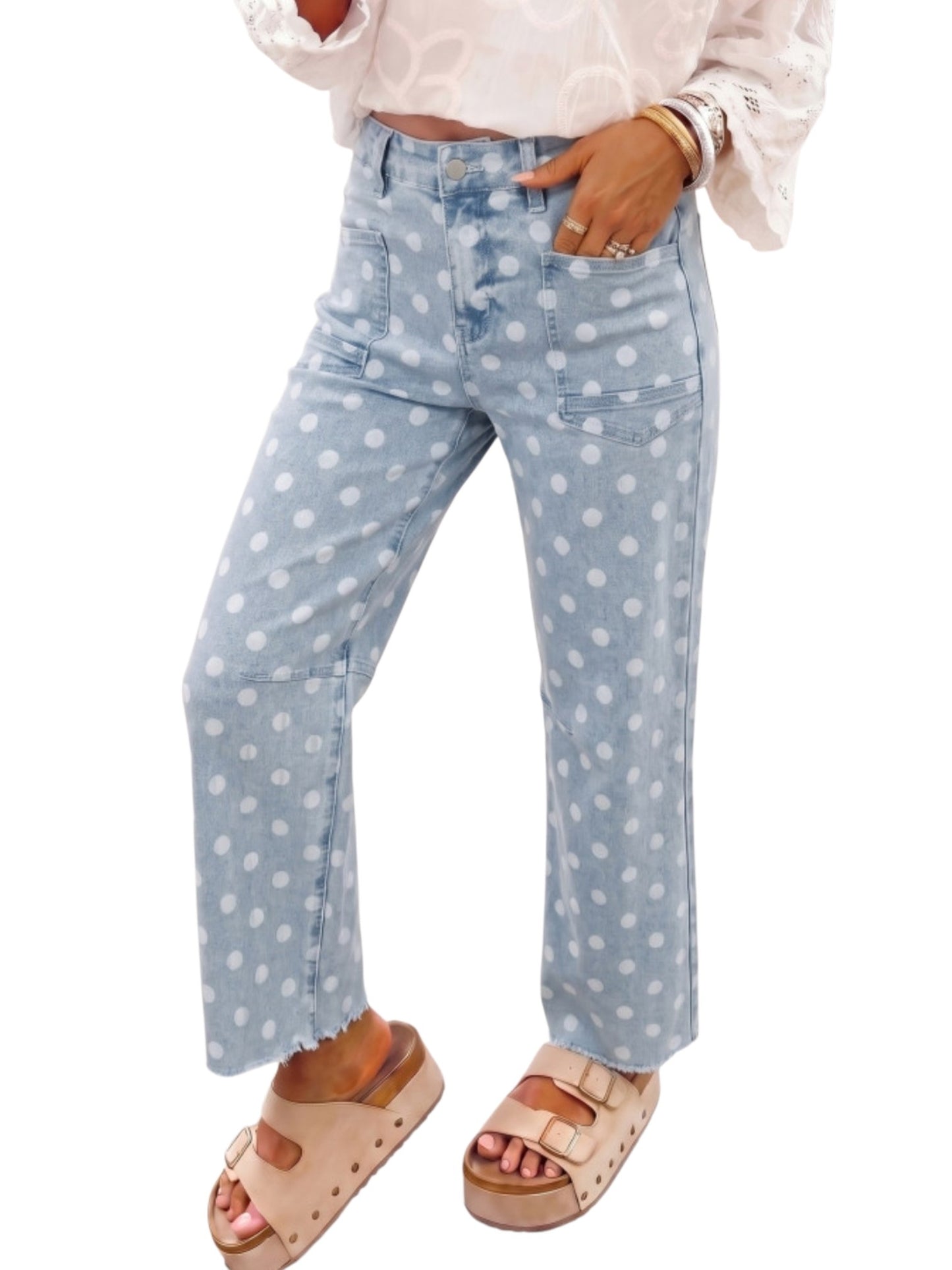 A person wearing light blue denim jeans with a white polka dot pattern, styled with a white blouse and beige platform sandals against a plain white background.