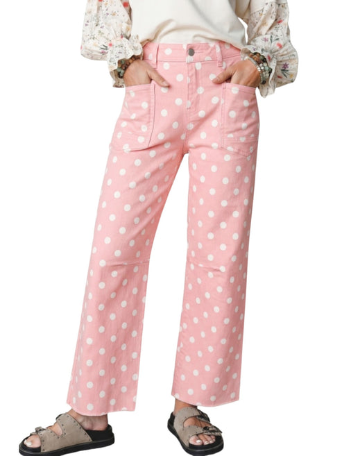 Pink wide-leg denim pants with a white polka dot pattern, shown on a model wearing a cream top and brown sandals against a white background.