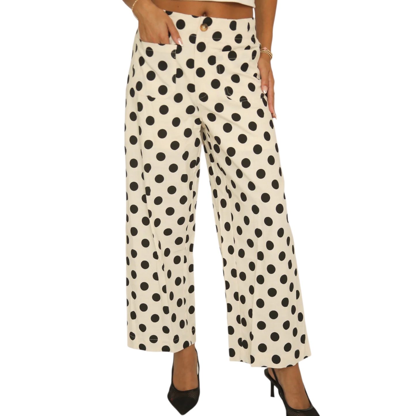 Front view of a woman wearing cream-coloured wide-leg trousers with a large black polka dot pattern, featuring a button closure and front patch pockets.