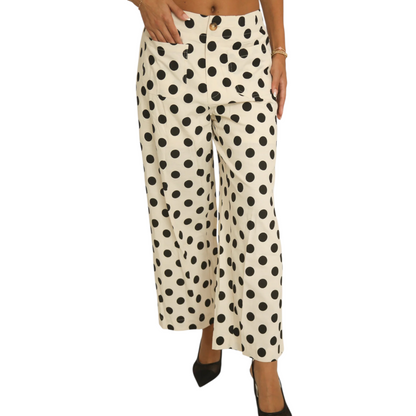 Front view of a woman wearing cream-coloured wide-leg trousers with a large black polka dot pattern, featuring a button closure and front patch pockets.