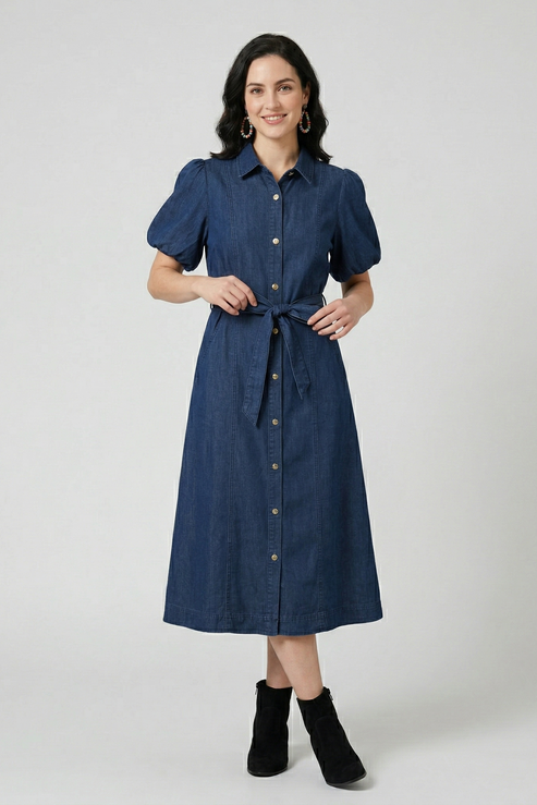 Front view of a model in a dark wash denim shirt dress featuring voluminous puff sleeves and a self-tie bow at the waist.