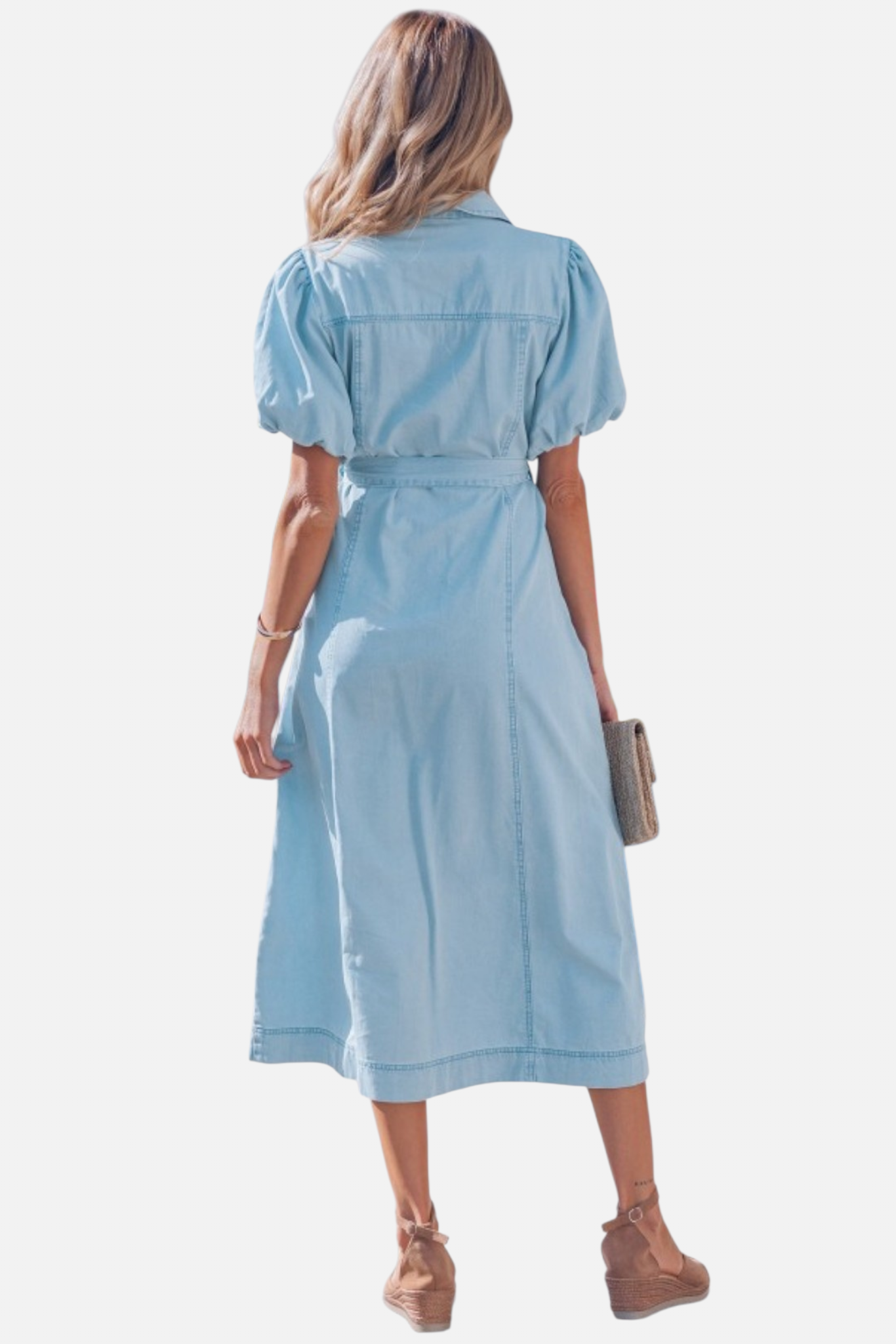 Rear view of a model in a light blue denim shirt dress featuring voluminous puff sleeves and a self-tie bow at the waist.