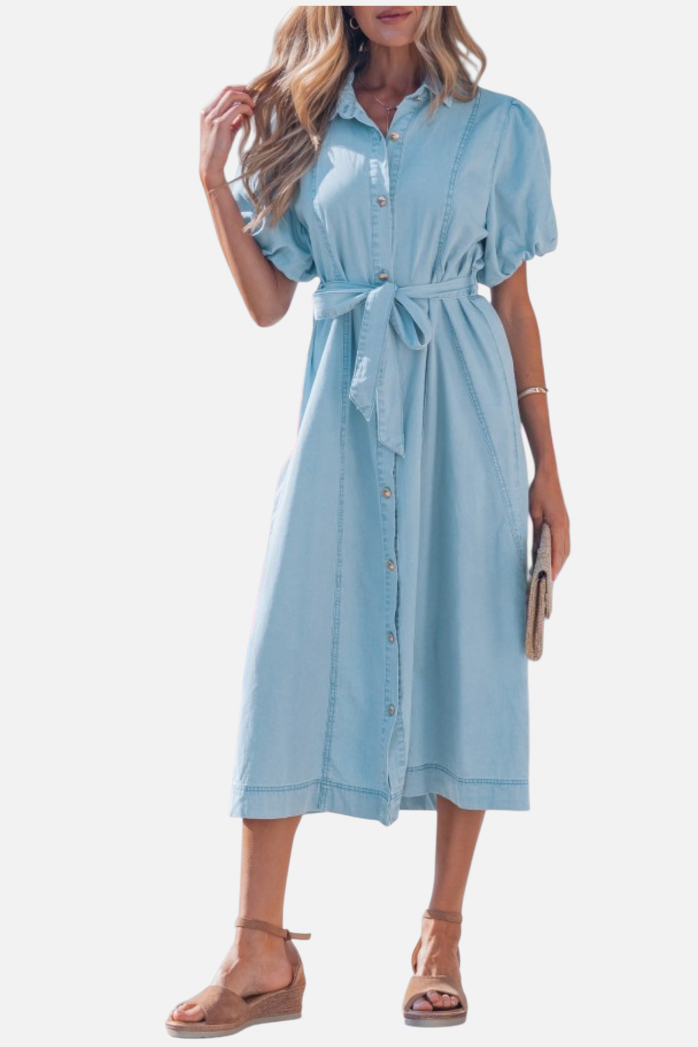 Closed up view of a model in a light blue denim shirt dress featuring voluminous puff sleeves and a self-tie bow at the waist.