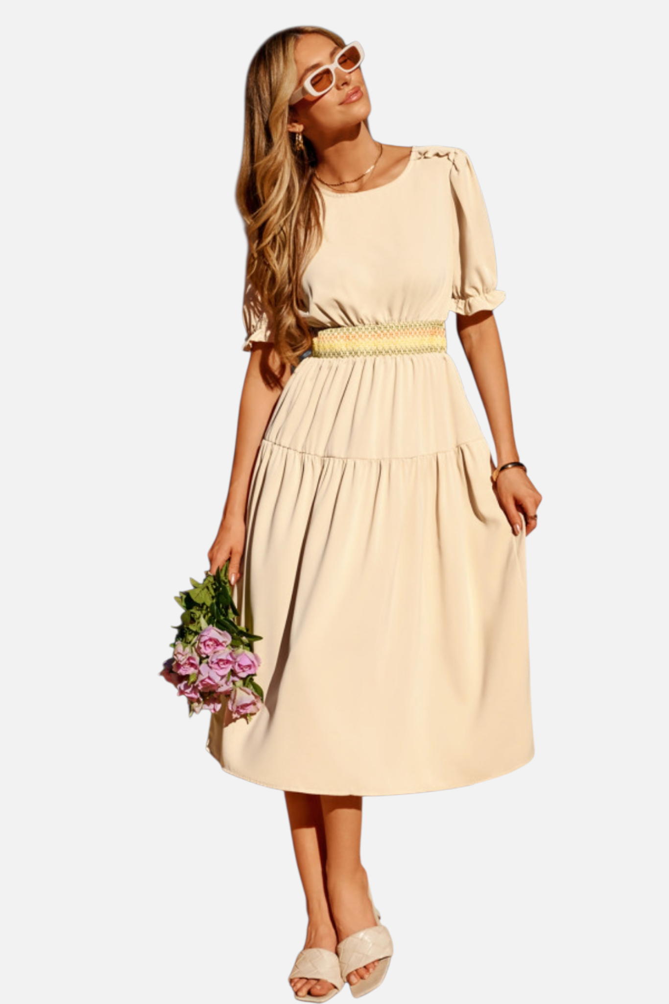 Woman wearing a beige dress holding flowers on a white background