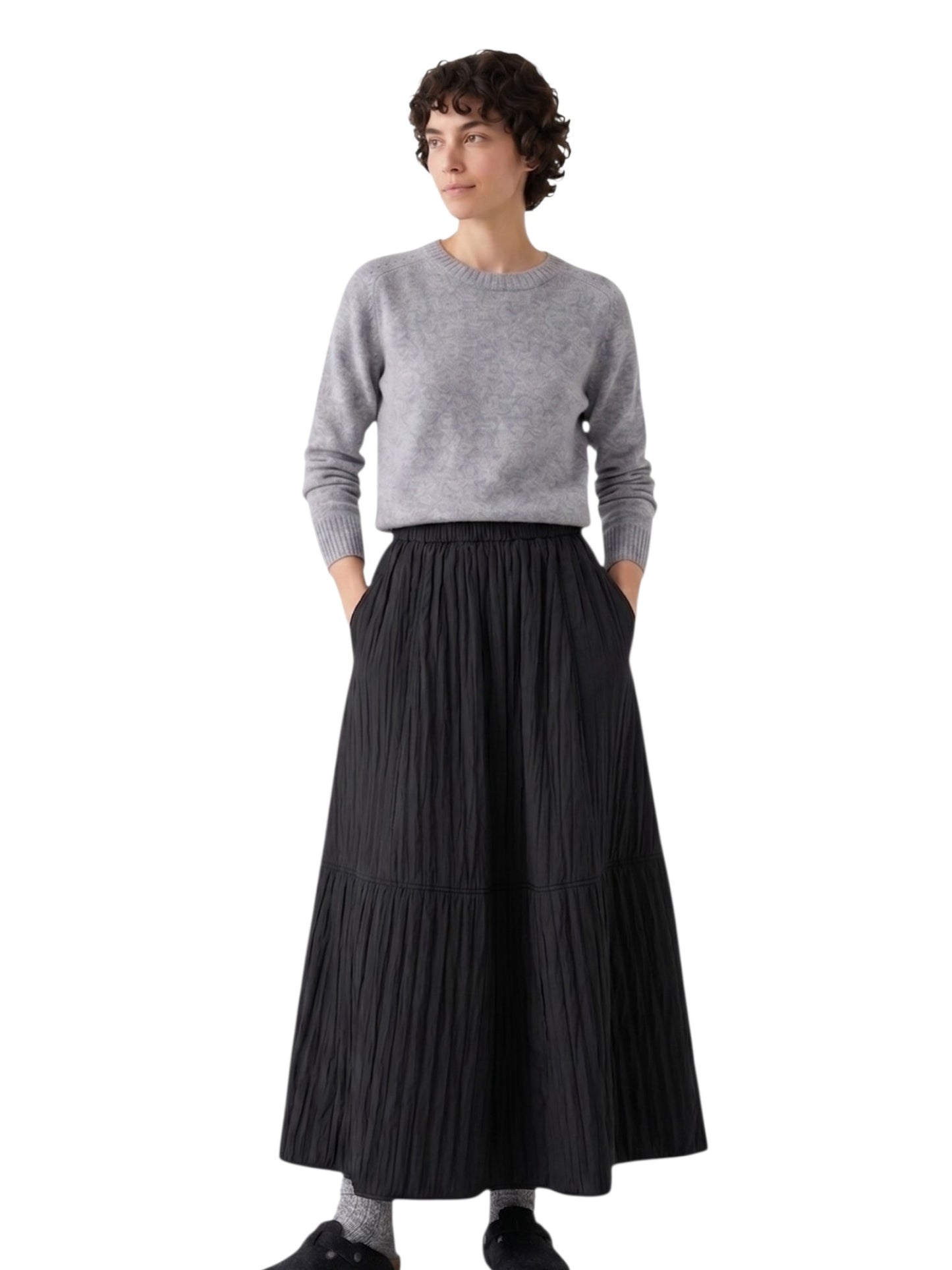 Full-length shot of the model wearing the black textured A-line maxi skirt with grey socks and clogs for a casual winter look.