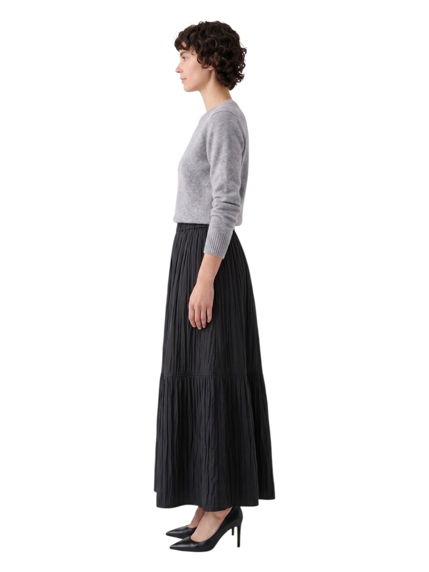 Woman wearing a gray sweater and black pleated skirt on a white background